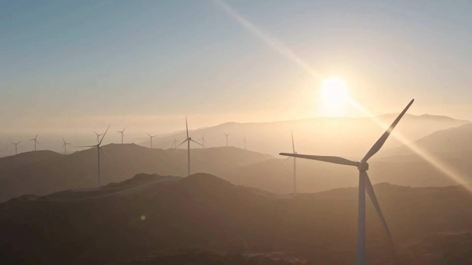 Aerogenerador al amanecer sobre las montañas